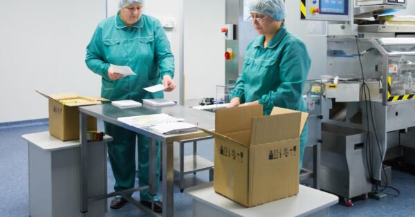 Pharmaceutical technicians work in sterile working conditions at pharmaceutical factory. Scientists wearing protective clothing