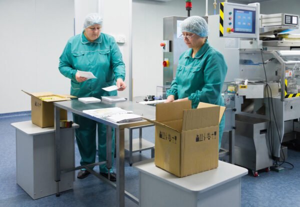 Pharmaceutical technicians work in sterile working conditions at pharmaceutical factory. Scientists wearing protective clothing