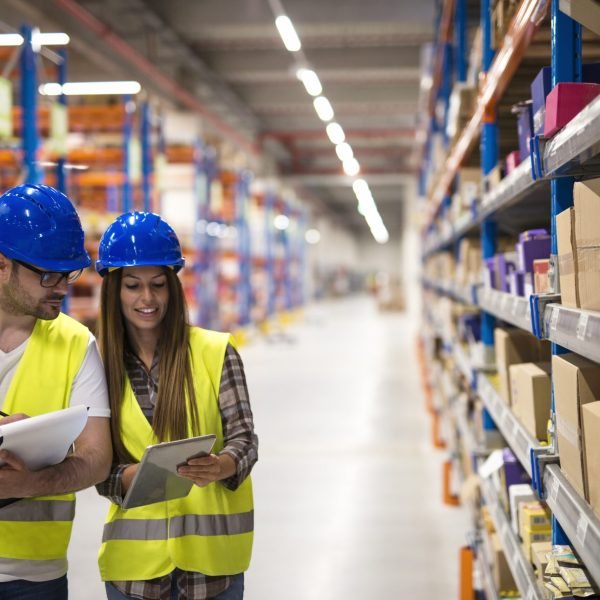 Warehouse employees working together on counting products and checking inventory in storage center.